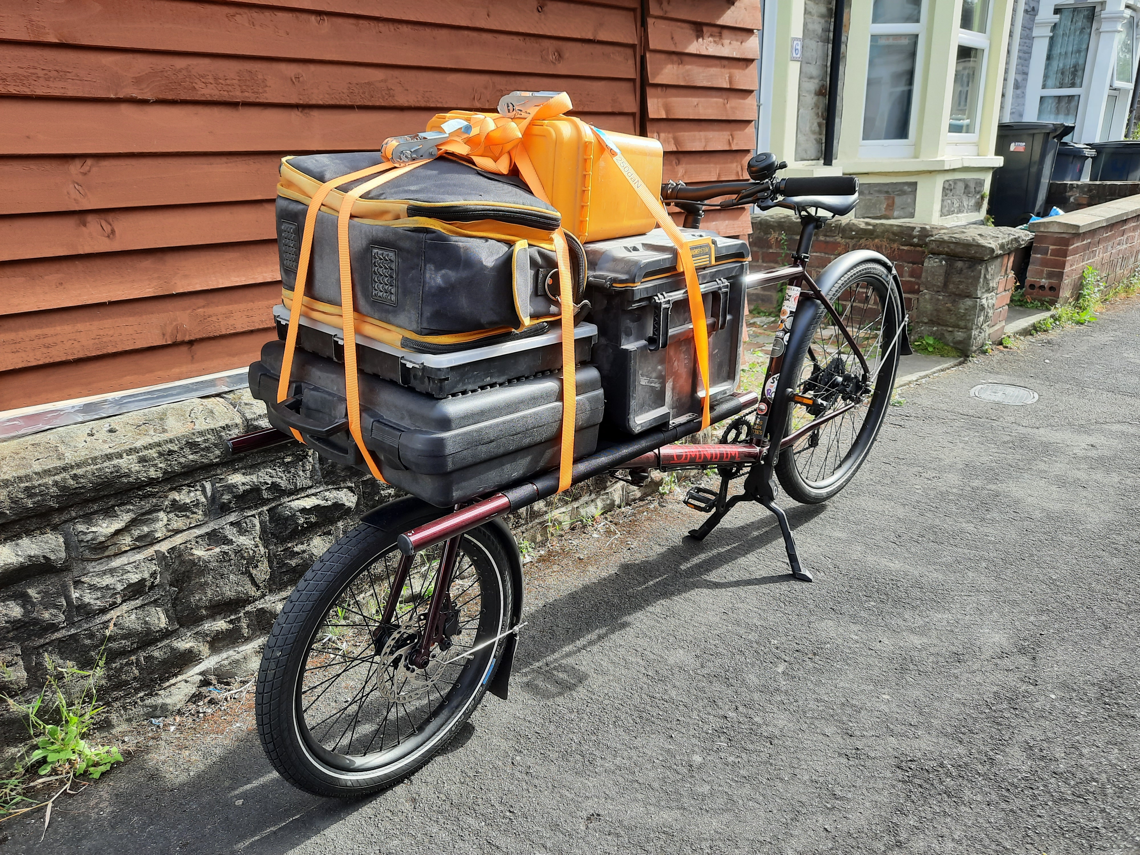 A maroon cargo bike loaded up with electrical tools and materials.
